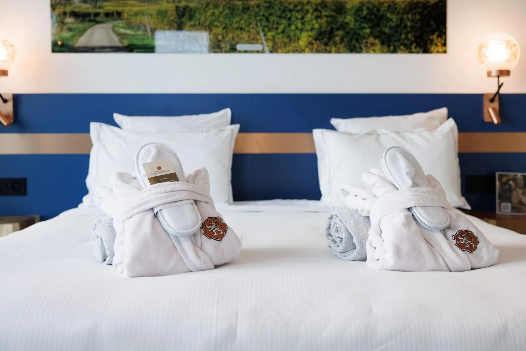 Chambre Husseren Collections — literie blanche, tête de lit bleu marine, œuvre d'art au mur