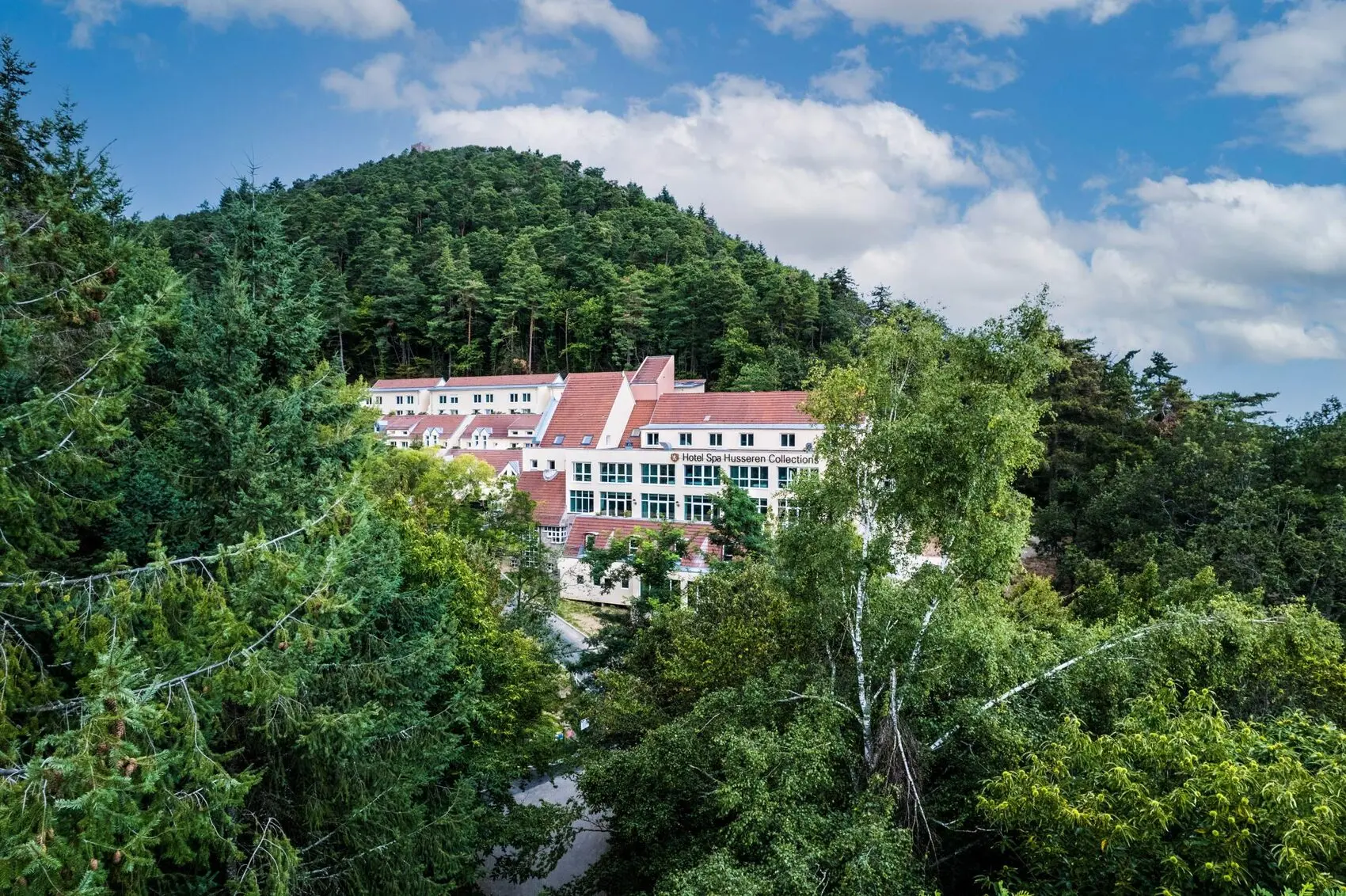 L'Hôtel Husseren Collections niché dans la forêt vosgienne, vu d'en haut, au pied des trois châteaux